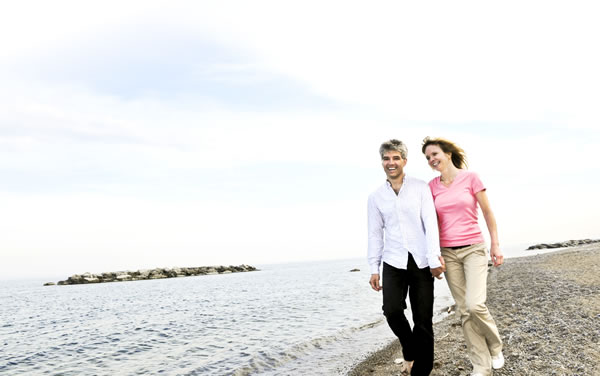Smiling middle-aged couple walking along waters edge